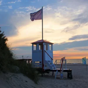 Der Badeturm auf Baltrum im Sonnenunergang. Eine Fahne weht im Wind.