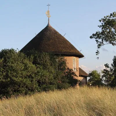 Im vorderen Teil ist ein Feld aus Strandhafer. Im Hintergrund ist ein Gebäude zu sehen.